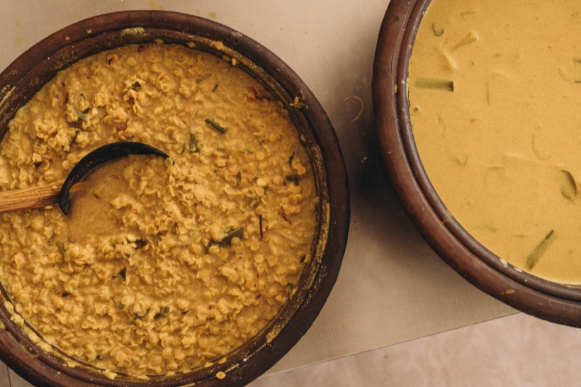 Two clay pots side by side, one of parippu dhal simmered with curry leaf and one of pale kiri hodi coconut gravy