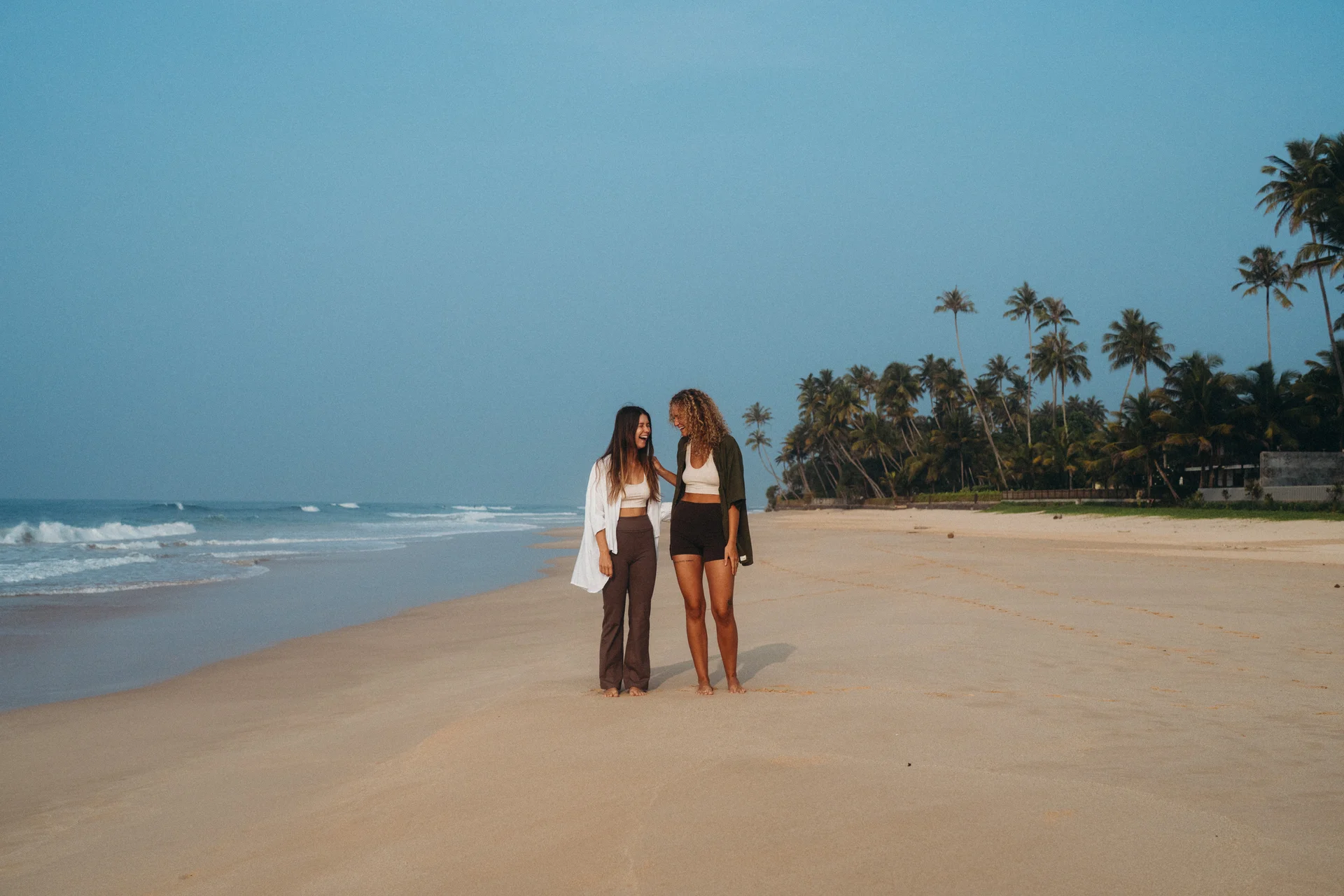 Two women standing on a palm-lined tropical beach in Sri Lanka